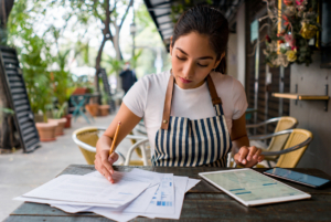 Female business owner working at a cafe doing the books on a table.